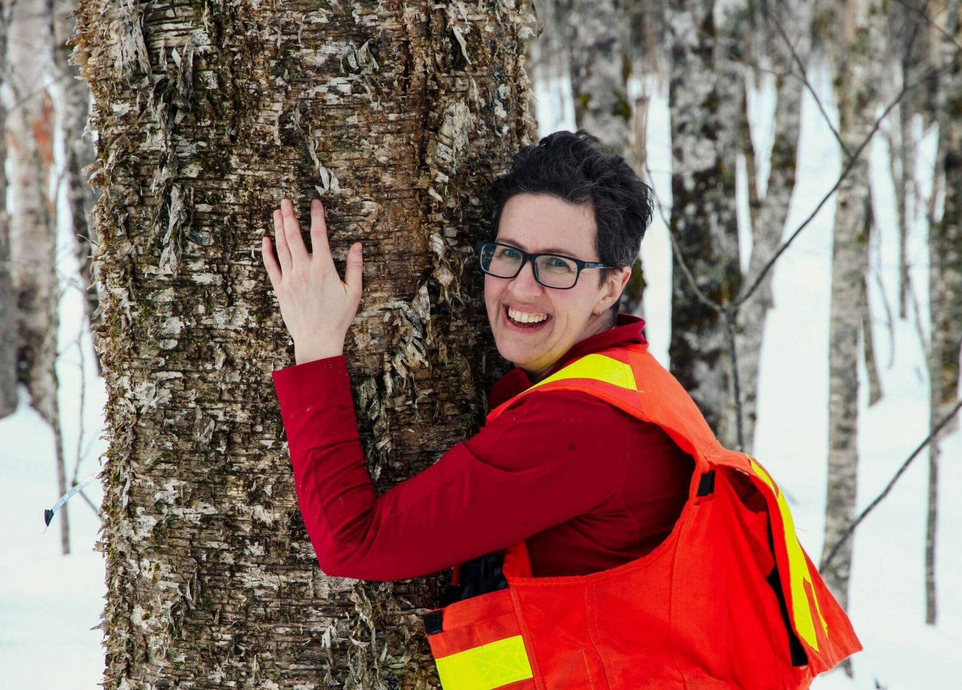 Woman hugging tree smiling towards camera